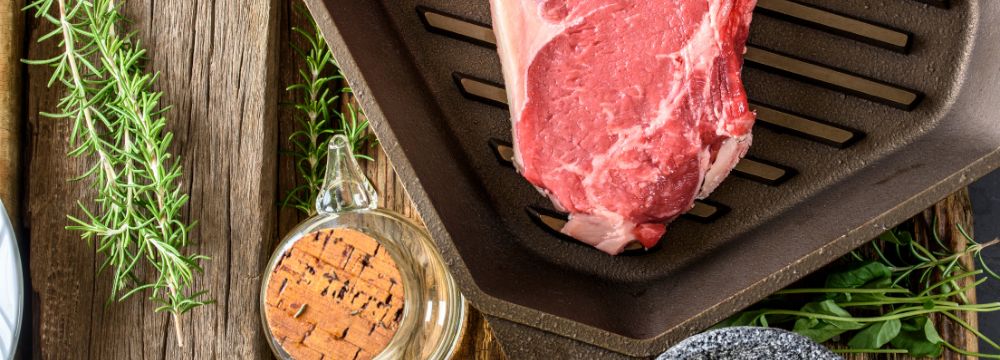 red meat being cooked on stove next to spices