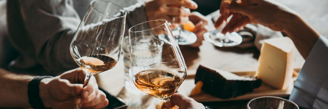 people at dinner table cheering with wine glasses 