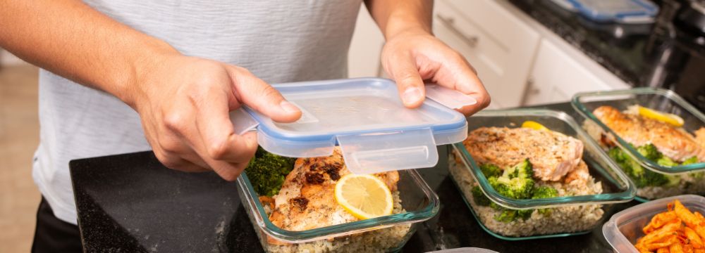 Man meal prepping dinner in Tupperware containers