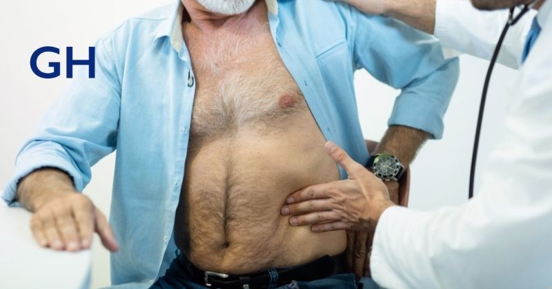 Hernia doctor's hands feel a man's abdomen to evaluate if a hernia needs surgical repair by Dr. Guillermo Higa