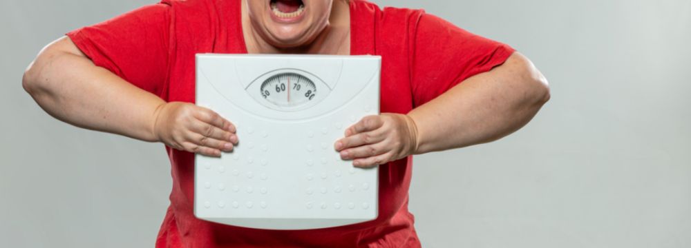 Woman holds scale frustrated with cycling through weight loss and gain before choosing weight loss surgery 