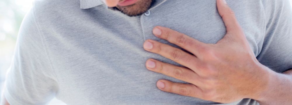Man holds chest as he struggles with heart burn wondering about treatment options for GERD