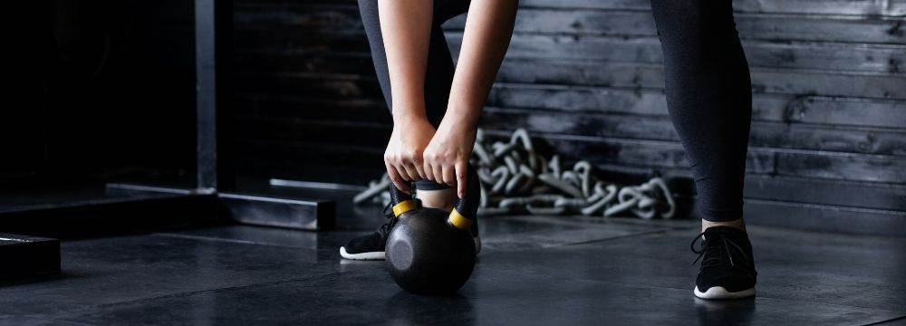 Woman in gym works on resistance exercise to build and maintain muscle mass during weight loss 