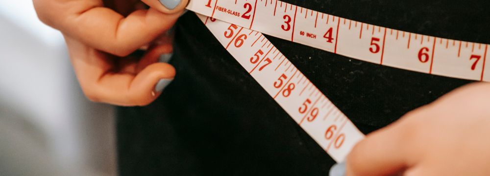 Close up of person measuring their waist with measuring tape