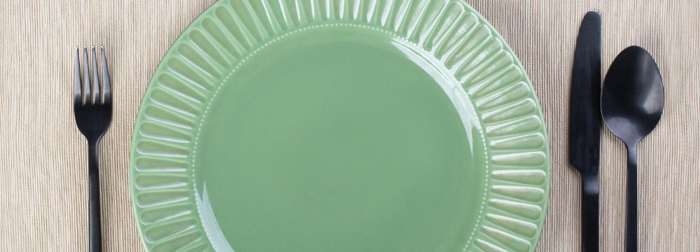 Empty green plate with utensils next to it